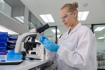 Scientist examining samples under a microscope in a modern laboratory setting during daylight hours