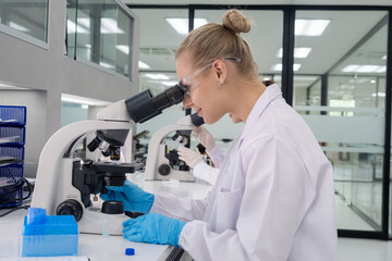 Scientist working diligently at a microscope in a modern laboratory setting during daylight hours