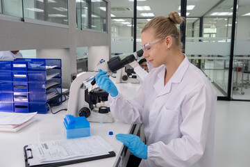 Scientist examines samples under microscope in modern laboratory during daytime