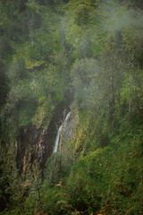 Majestic waterfall cascading through lush green hills serene nature scene foggy environment scenic viewpoint