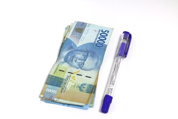 Indonesian Rupiah Banknotes and a Vibrant Purple Pen Arranged on a Pure White Surface