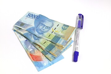 Indonesian Rupiah banknotes beside a purple pen on a white background Financial planning concept