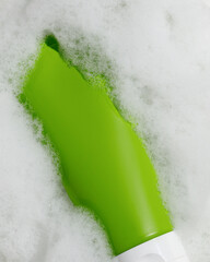 Empty green cosmetic tube in foamy water – clean skincare concept. Mockup. Packaging for cream,...