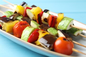 Vegetarian barbecue. Skewers with tasty grilled vegetables on light blue wooden table, closeup