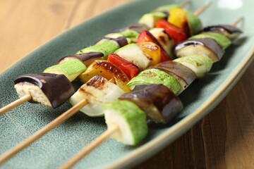 Vegetarian barbecue. Skewers with tasty grilled vegetables on wooden table, closeup