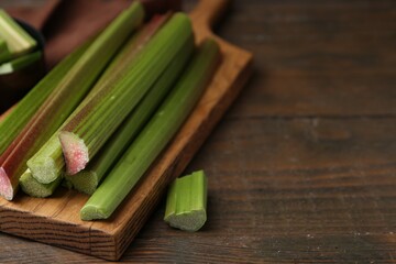 Fresh rhubarb stalks on wooden table, closeup. Space for text