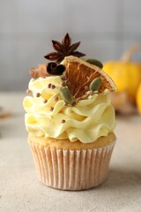 Delicious cupcake with color cream and spices on grey table, closeup
