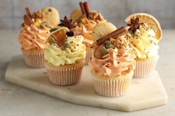 Delicious cupcakes with colorful cream, spices, cookies and nuts on grey table, closeup