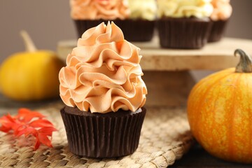 Delicious cupcake near pumpkin on table against grey background, closeup. Autumn atmosphere