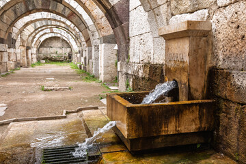 Modern water fountain installed within ancient Roman archway of Smyrna Agora ruins in Izmir Turkey