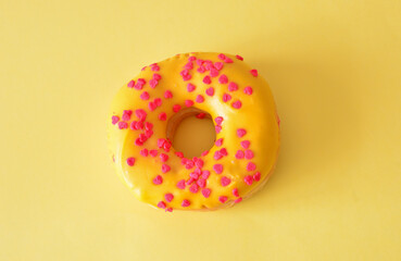 Delicious Donut with Pink Heart Sprinkles on Yellow Background close up