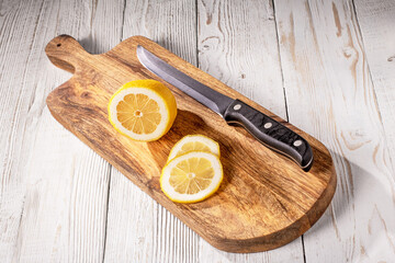 A freshly sliced lemon with a sharp kitchen knife on rustic wooden table