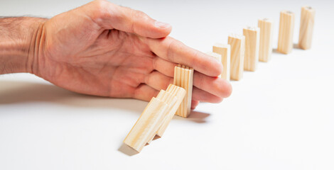 Man hand stopping domino effect on white background. Business concept.