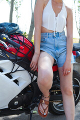 Biker girl sitting on a motorcycle. Biker girl in shorts and a white tank top.