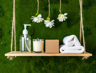 Wooden shelf with soap dispenser candle and towels on moss background