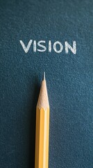 A sharpened yellow pencil leans against a dark surface, with the word "VISION" written in white chalk above it, conveying creativity and inspiration.