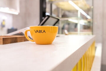 Close-up view of a steaming cup of coffee in a white ceramic mug placed on a vibrant yellow saucer, showcasing rich textures and inviting warmth in a cozy setting