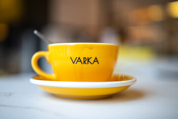 Close-up view of a steaming cup of coffee in a white ceramic mug placed on a vibrant yellow saucer, showcasing rich textures and inviting warmth in a cozy setting