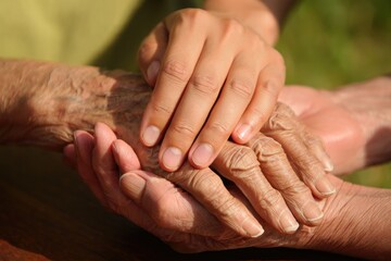 Fototapeta premium Close-up of young and old hands holding care support