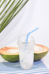 Young Coconut Water in a Cup and Halved Young Coconut on a Placemat, White Background
