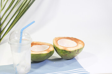 Young Coconut Water in a Cup and Halved Young Coconut on a Placemat, White Background