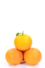 Four Valencia Oranges with a Leaf Arranged in a Pyramid on a White Background
