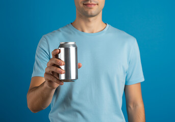 Refreshing drink concept, man offers a cool beverage in a sleek aluminum can against a vibrant blue backdrop, perfect for summer ads and promotions