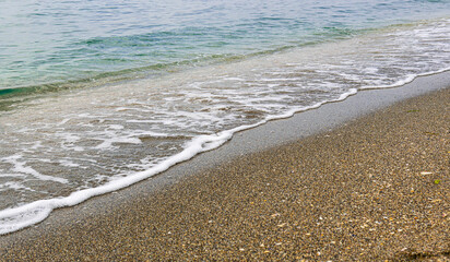 Foam, sand, and turquoise water close-up.