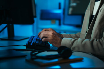 Close-up of programmer hands typing keyboard, working on coding, AI system, data security, and cloud computing in dark office.