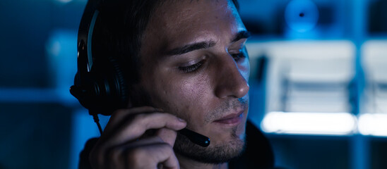Close-up of Caucasian male IT support with headset, working night shift, providing technical assistance and communication service.