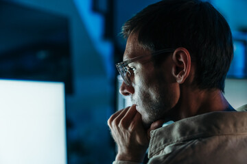 Caucasian web developer and IT support specialist coding in dark office, working on cybersecurity, hacking prevention and cloud computing.