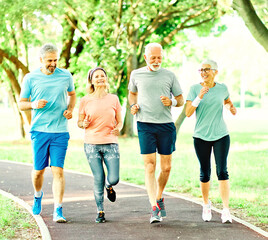 Smiling active senior people jogging together in the park
