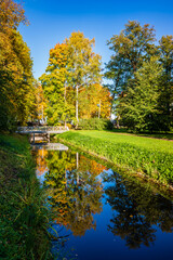 Beautiful autumn landscape. Trees with yellow leaves reflected in the water in the park, Alexandria Park, Peterhof, Saint Petersburg, Russia