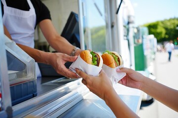 Food vendor handing burgers to a customer at a food truck