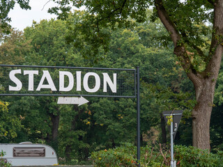 A clear "STADION" sign with an arrow pointing right, set against a dense green forest