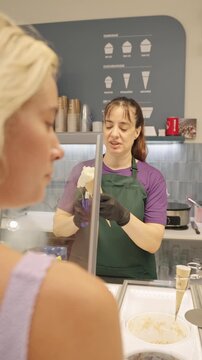 Ice cream parlor employee serving cone to customer