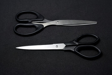 Two scissors on a black background. Stationery scissors.