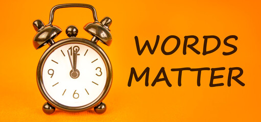 Words matter symbol. Concept word Words matter on beautiful orange paper. Beautiful black alarm...