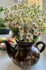 bunch of wildflowers camomiles in teapot vase on table summer decoration vibes