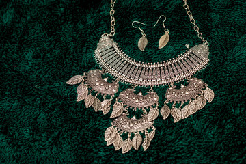 Elegant Silver Necklace and Earrings Set on a Green Surface. Silver Necklace and Earrings Set on Green Fabric. silver necklace and earrings