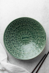 Top view of green ceramic plates on a marble table, handmade green ceramic plate on a white background