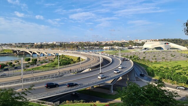 There are many cars driving on the highway near the water