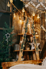Decorated Christmas interior with glowing light bulbs and garland with evergreen pine branches and cones. Holiday decoration and festive mood.