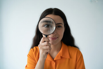 Woman peers through magnifying glass at the camera