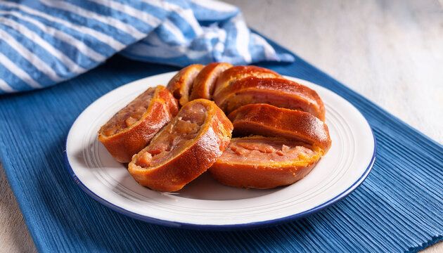 Sliced Traditional Portuguese Folar On A White Plate With A Blue Napkin