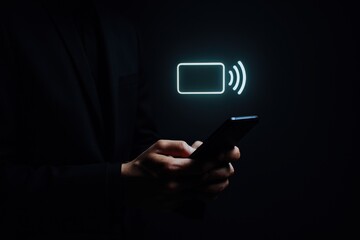 Businessman holding smartphone with glowing hologram credit card icon for secure mobile payments and digital wallet technology in dark background

