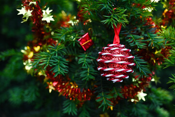 Close-up of a decorated Christmas tree branch with shiny red bauble, tinsel, golden and red decorations. Ideal for creating a New Year's mood, decorating winter sales or holiday cards.