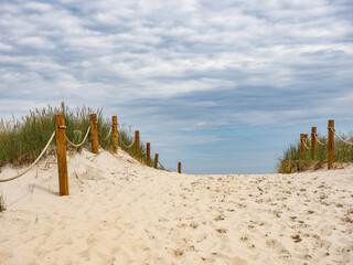 Sunny Beach Path Through Sand Dunes With Wooden Posts And Rope Fencing