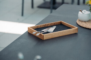 Tortenheber im Holztablett auf modernem schwarzen Tisch – minimalistisches Café-Design