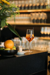 Aperol Spritz Cocktail im Weinglas an eleganter Bar mit Zitrusfrüchten